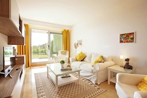 A modern living room with a glass coffee table, white sofas, a television, and a sliding glass door leading to a balcony. - Ground floor apartment with amazing views-Fl8-1 (Ojen)
