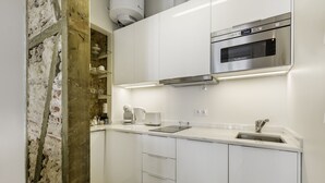 Een moderne keuken met witte kastjes, een roestvrijstalen oven en een inbouw koffiezetapparaat.