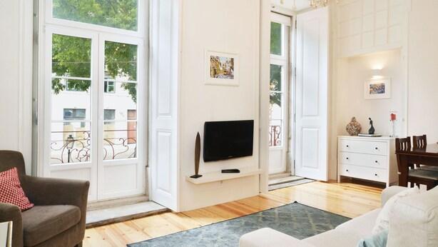 Een woonkamer met een flatscreen televisie, een bank, een stoel en een eethoek met een tafel en stoelen.