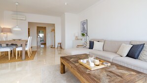A modern living room with a wooden coffee table, a sofa, and a dining area with chairs and a table.