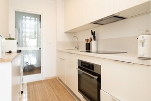 A modern kitchen with white cabinetry, a built-in oven, a stainless steel sink, and a window with a view.