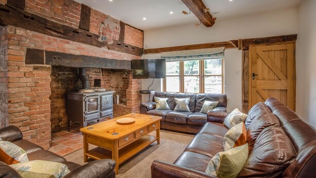 Una sala de estar acogedora con chimenea de ladrillo, sofás de cuero y una mesa de centro de madera.