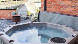 Un jacuzzi con una pared de ladrillo y un banco de madera al fondo.