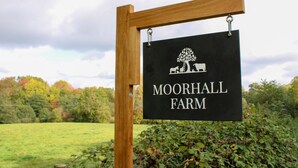 Letrero de Moorhall Farm con un poste de madera y fondo negro.