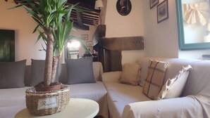 A cozy living room with a sofa, a round table, and a potted plant. - Podere I Rovai-apt IL RIFUGIO-amazing view Tuscany (Reggello ( Firenze ))
