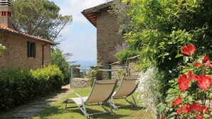 A stone building with a tiled roof, a pathway, and two beige lounge chairs. - Podere I Rovai-apt IL RIFUGIO-amazing view Tuscany (Reggello ( Firenze ))