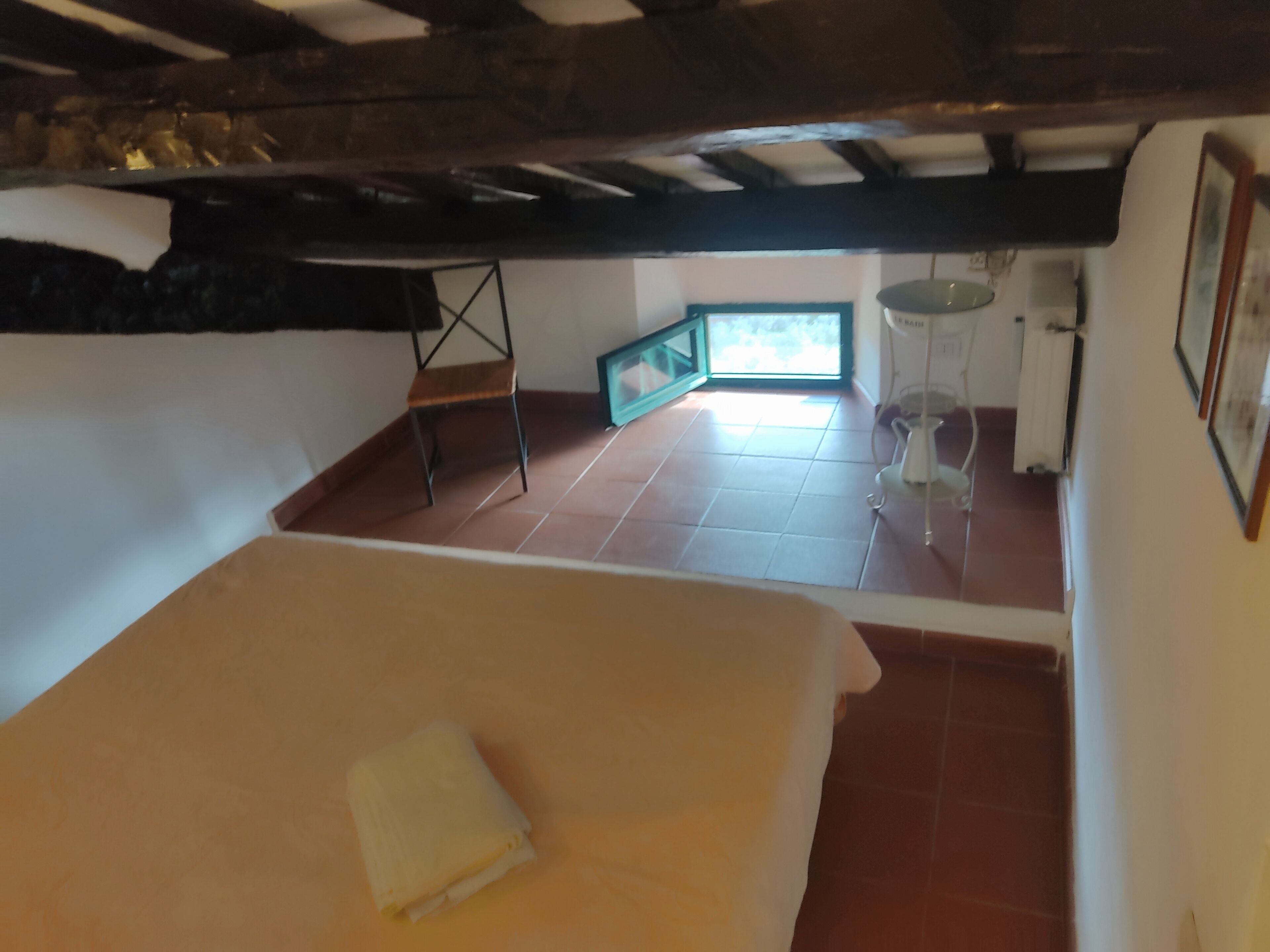 Une chambre à coucher avec un lit, une chaise, une petite table et une fenêtre.