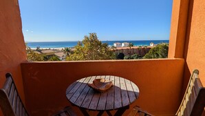 A balcony with a wooden table and two chairs, overlooking a beach and ocean. - 201 Apartamento La Duna (Tarifa)
