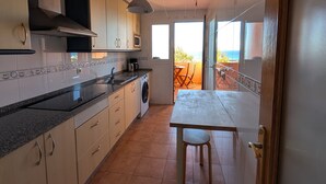 A kitchen with a dining area, a washing machine, and a view of the sea through a glass door. - 201 Apartamento La Duna (Tarifa)