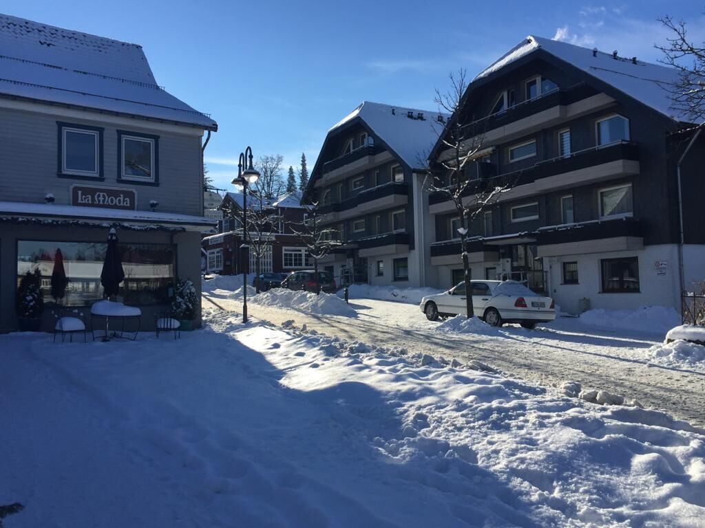 Una calle nevada con edificios, incluyendo un hotel que muestra el letrero 'La Moda'.