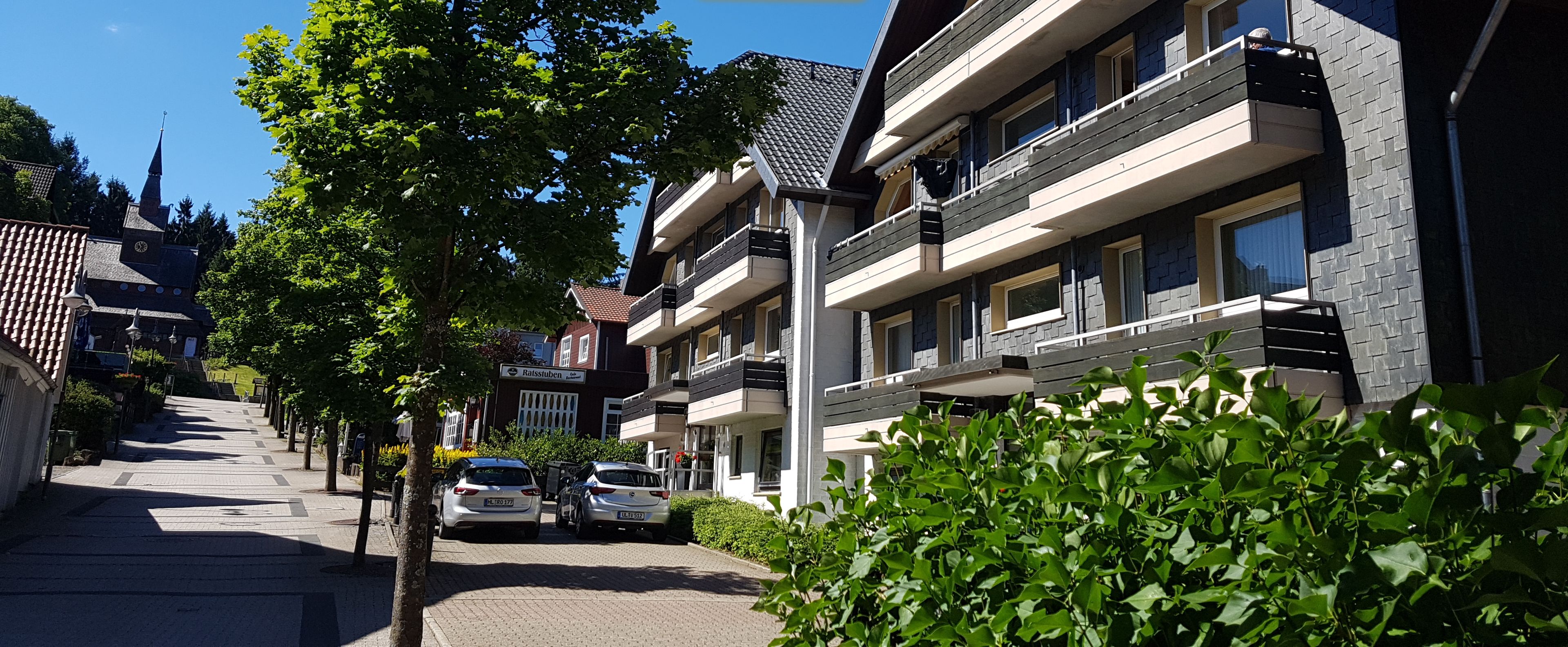 A modern multi-story building with balconies, a clear sky, and a sign for 'GlücksKlee'.