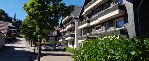 Un edificio moderno de varios pisos con balcones, cielo despejado y un letrero que dice 'GlücksKlee'.