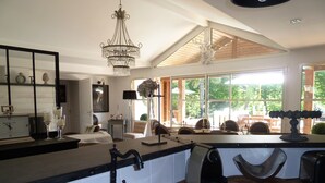 A modern kitchen with a large window, a chandelier, and a dining area with a view. - Villa Esprit de Famille in Moliets et Maa, close to the ocean and golf course (moliets et maa)