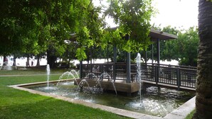 Een park met een fontein, een kiosk en een wandelpad.