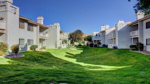 A residential area with houses featuring white exteriors and red-tiled roofs, arranged in a row with a grassy slope in the foreground.