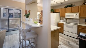 A modern kitchen with wooden cabinets, a white countertop, and stainless steel appliances.