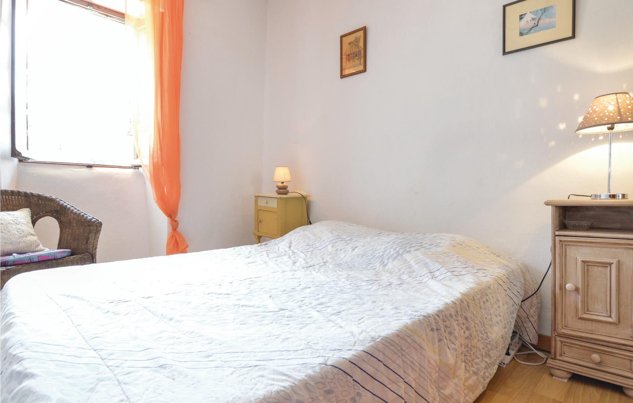 A bedroom with a bed, a nightstand, a lamp, a chair, and a cabinet.