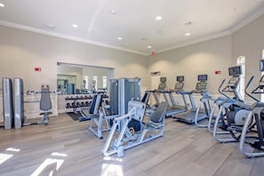 A gym with various exercise equipment, including treadmills, weight machines, and dumbbells.