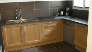 Een keuken met houten kastjes, een roestvrijstalen spoelbak en een vaatwasser.