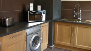 Een keuken met een wasmachine, een broodrooster en een magnetron op het aanrecht.