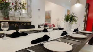 A dining table set with white plates, silverware, and black napkins. There are vases with flowers and a potted plant on the table. - Just listed - The Enticing Villa Cardona, Magnesia Falls, Rancho Mirage (Rancho Mirage)