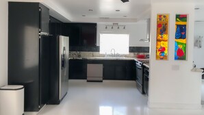 A modern kitchen with black cabinets, stainless steel appliances, a marble countertop, and a ceiling fan. - Just listed - The Enticing Villa Cardona, Magnesia Falls, Rancho Mirage (Rancho Mirage)