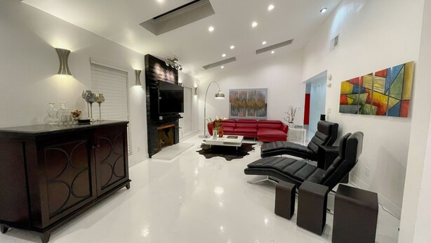A modern living room with a red sofa, black leather chairs, a coffee table, and a flat-screen TV. - Just listed - The Enticing Villa Cardona, Magnesia Falls, Rancho Mirage (Rancho Mirage)