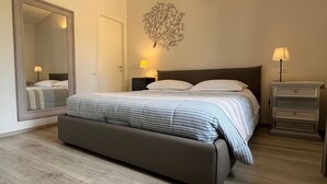 Une chambre moderne avec un grand lit, des lampes de chevet, un luminaire fixé au mur et un grand miroir.