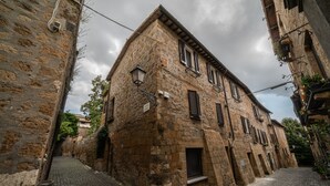 Une ruelle étroite pavée, bordée de bâtiments historiques en pierre, dotés de volets traditionnels et d’une enseigne indiquant la présence d’un restaurant.