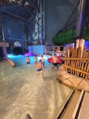 A water park with a large indoor pool, slides, and a wooden play structure.
