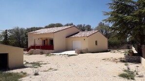 A two-story house with a tiled roof, a front porch, and a gravel driveway.