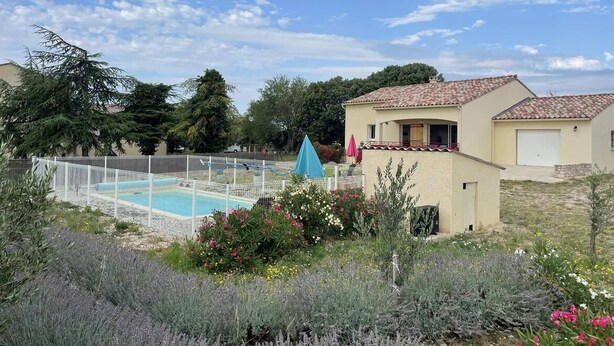 A residential area with a swimming pool, a small house, and a fenced garden.