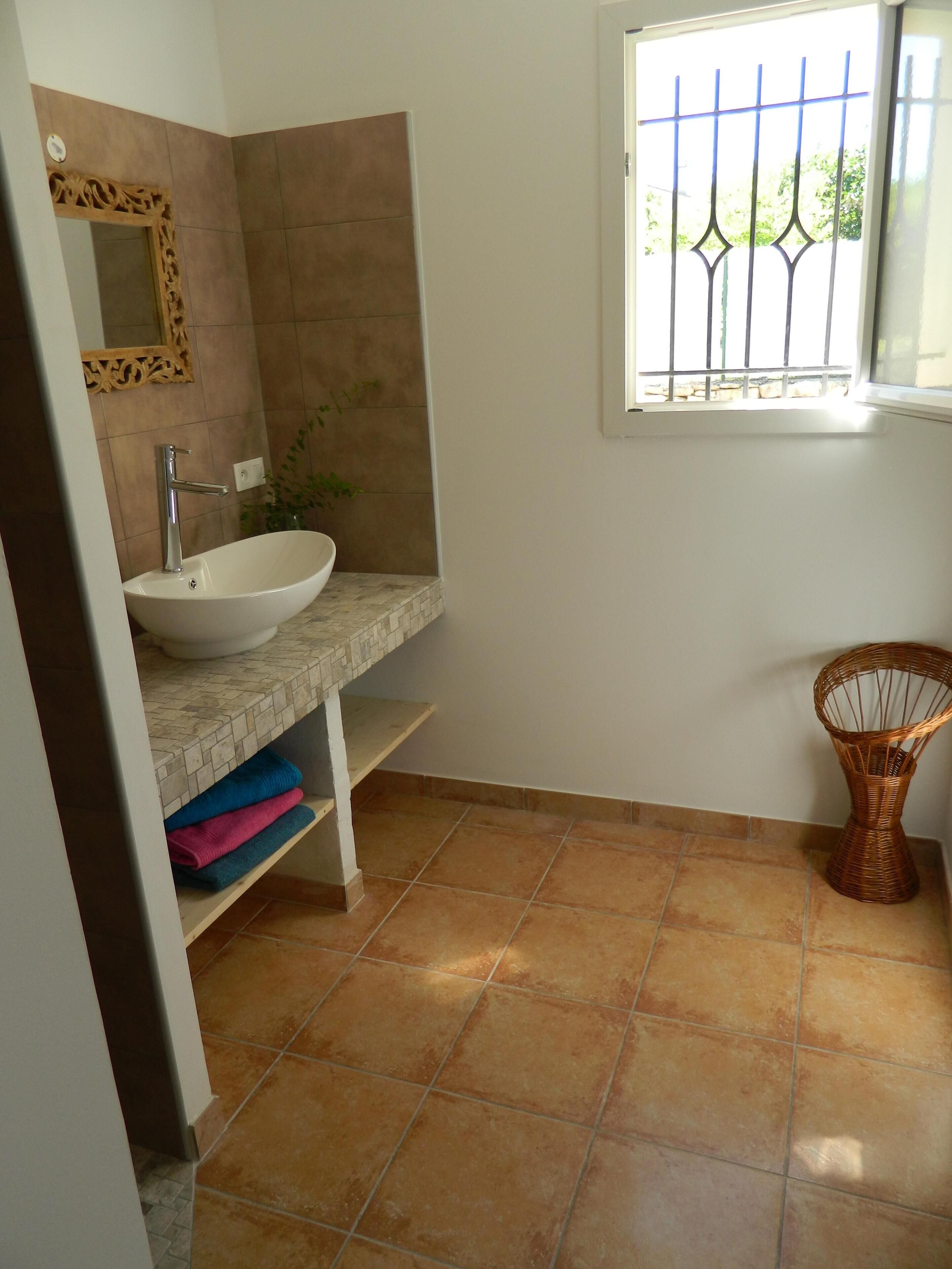Un baño con un lavamanos blanco, un espejo y una ventana con barrotes.