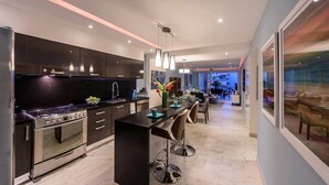 Una cocina moderna con armarios oscuros, electrodomésticos de acero inoxidable y una isla central con taburetes de bar.