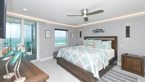 A bedroom with a bed, a nightstand, a ceiling fan, a window, and a view of the ocean. - Crystal Sands Tower Unit 903 - Beachfront (Sarasota)