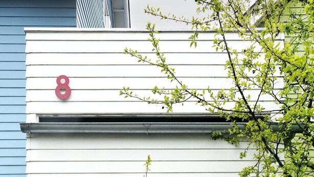 A two-story house with a front door, a flower decoration, and a number '8' on the wall.