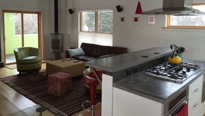 A modern kitchen with a central island, a built-in stove, and a large window providing natural light.