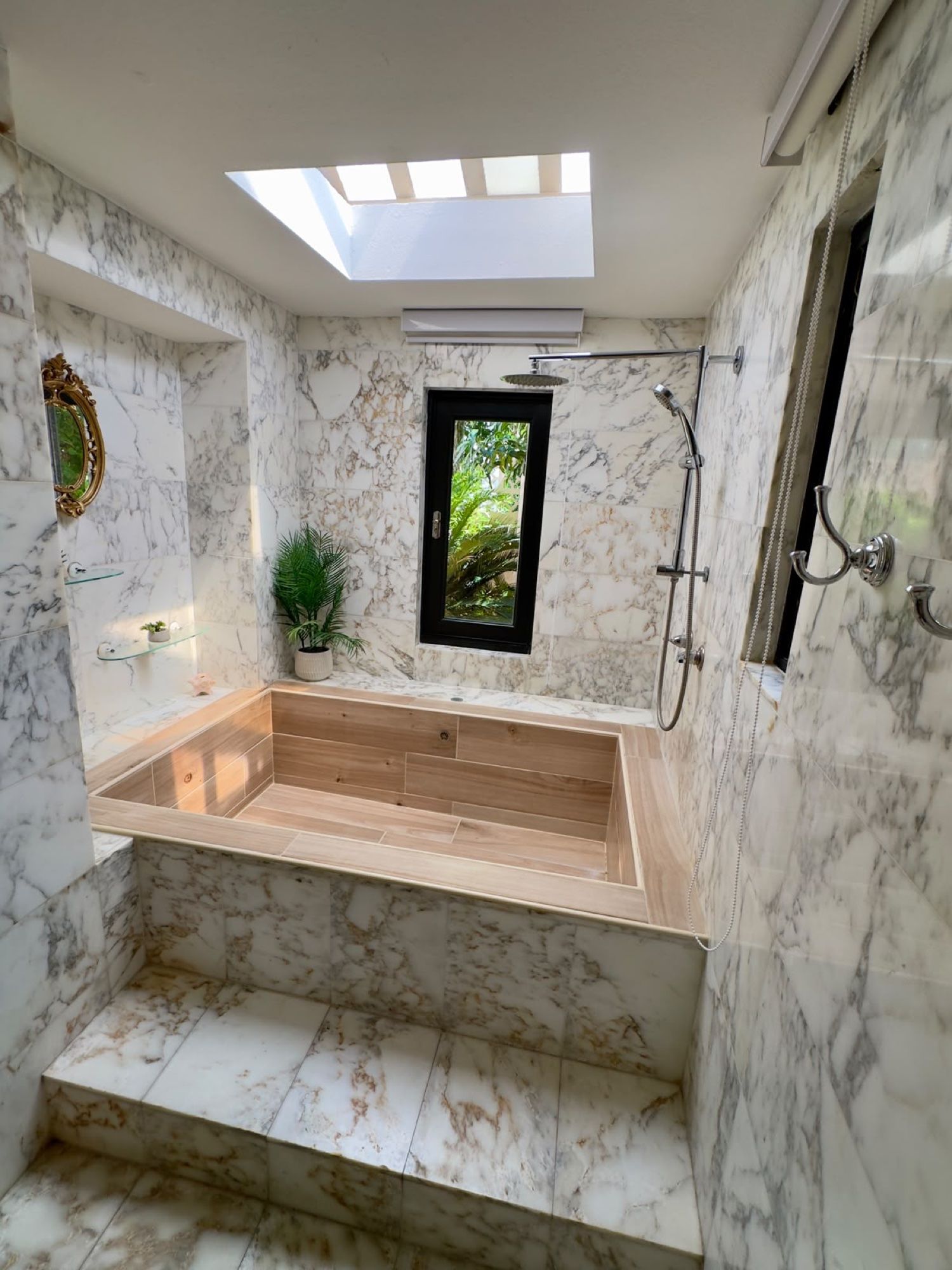 A modern bathroom with a skylight, a freestanding bathtub, and a shower area.