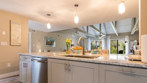 Una cucina moderna con una grande isola, elettrodomestici in acciaio inossidabile e vista sull'esterno.
