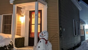 Una casa con un muñeco de nieve en el frente, una entrada iluminada y el número 4 en la puerta.