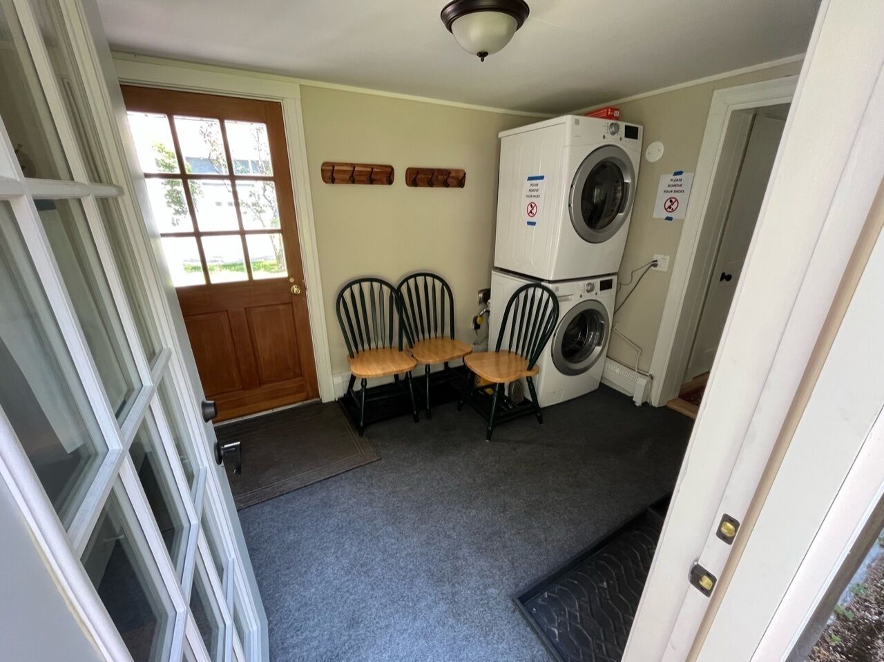 A laundry room with a washing machine, a dryer, and two chairs.