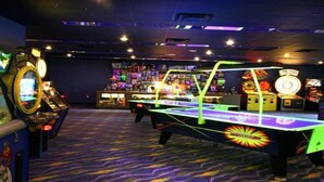Ein Raum mit Billardtisch, Spielautomaten und einer Auswahl an verschiedenen Spielgeräten.