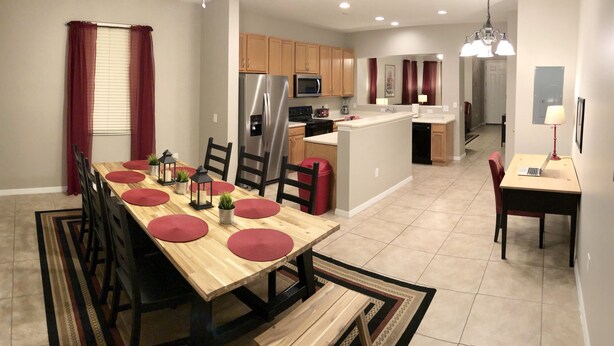 A modern kitchen with stainless steel appliances, wooden cabinets, and a dining area with a wooden table and chairs.