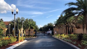 A gated entrance with a clear pathway, palm trees, and a street lamp.
