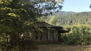 Een rustieke hut omgeven door dicht bos en bergen.