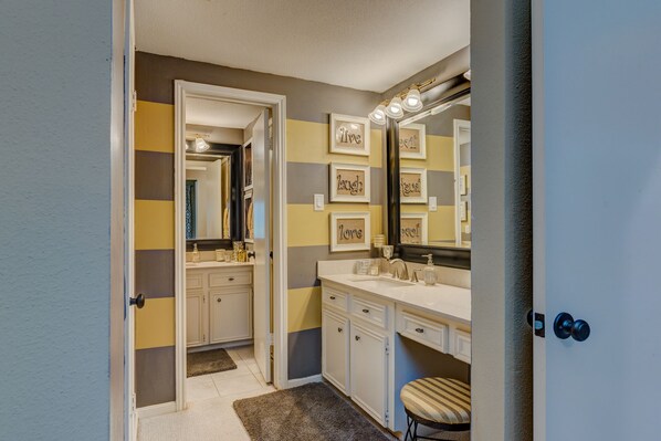 A bathroom with a vanity, a large mirror, and decorative wall art. - WATERFRONT CONDO WITH AMAZING VIEW OF SUNRISE, SUNSET AND EXPANSIVE OPEN WATERS (Montgomery)