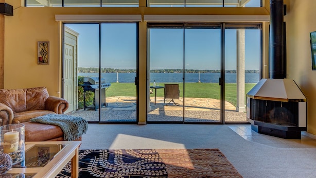 A spacious living room with a large sliding glass door leading to a patio with a grill and outdoor seating. - WATERFRONT CONDO  WITH AMAZING VIEW OF SUNRISE, SUNSET AND EXPANSIVE OPEN WATERS (Montgomery)