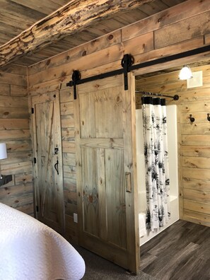 Habitación con paneles de madera, una cama, una puerta corredera y una zona de ducha.