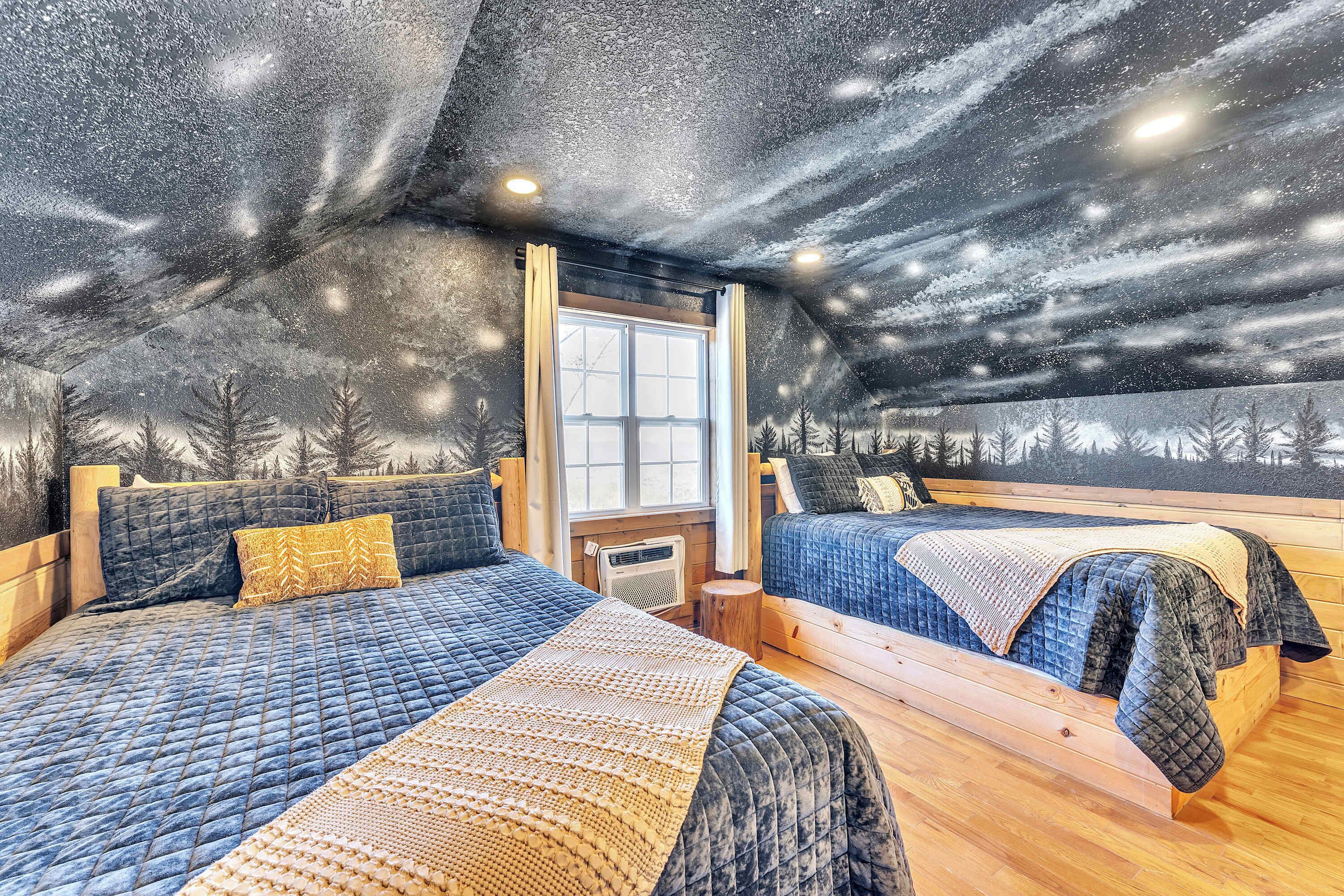Una habitación acogedora con dos camas, un ventanal grande y un techo que evoca un cielo estrellado.