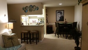 Un espacio habitable compacto con kitchenette, comedor y zona de estar con lámpara y cojines.